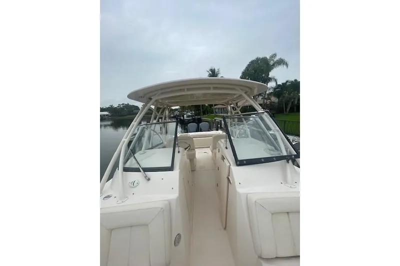 Slide: The Image of 2015 Grady-White Freedom 285 boat interior with seating and windshield, docked on water. - 2