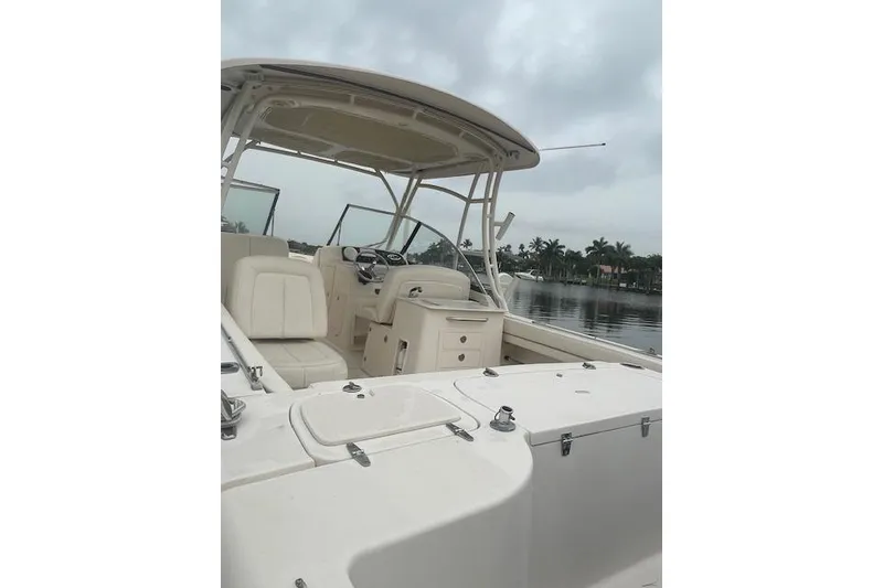 Slide: The Image of 2015 Grady-White Freedom 285 boat interior with seating and helm, docked by the water. - 7