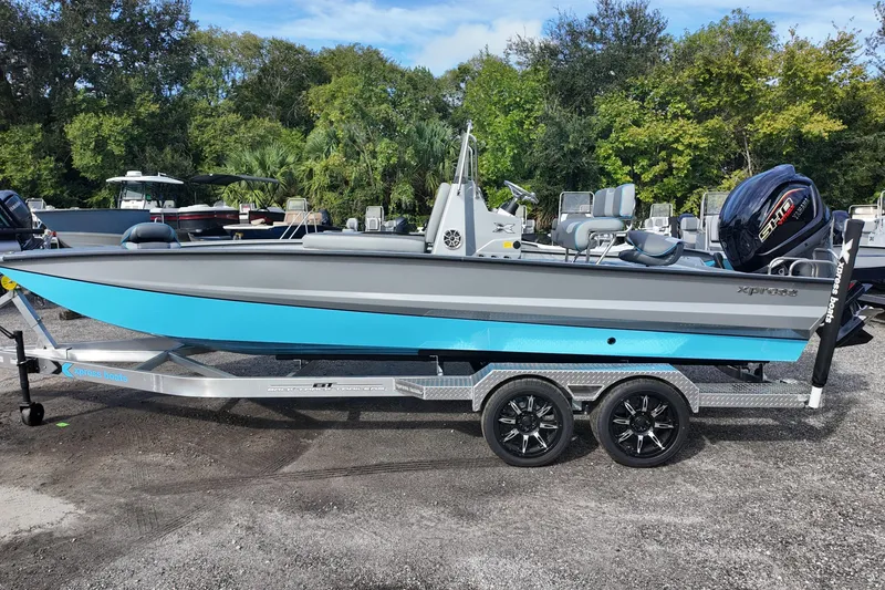 The Image of 2026 Xpress X23B Bay Lounge boat on trailer, featuring sleek design and vibrant blue accents. - 0