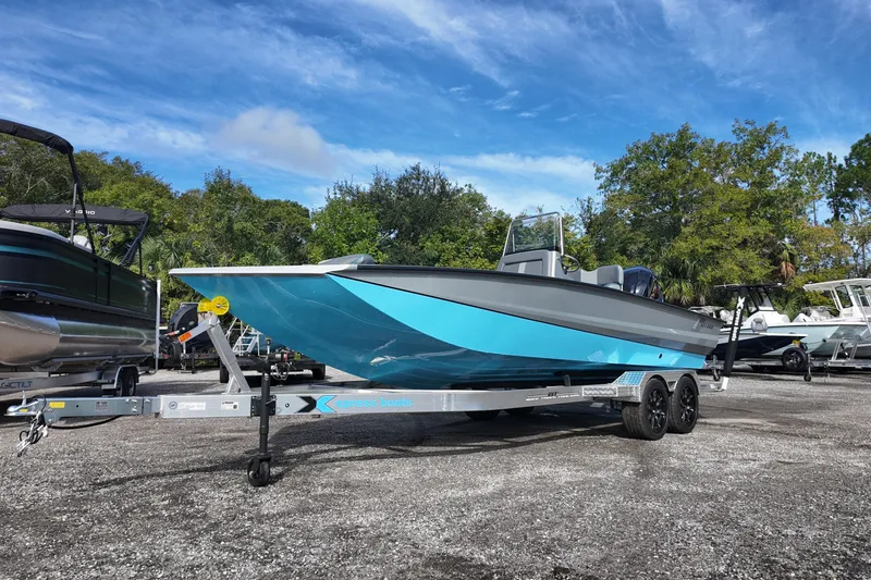 Slide: The Image of 2026 Xpress X23B Bay Lounge boat on trailer, vibrant blue hull, outdoor display. - 2