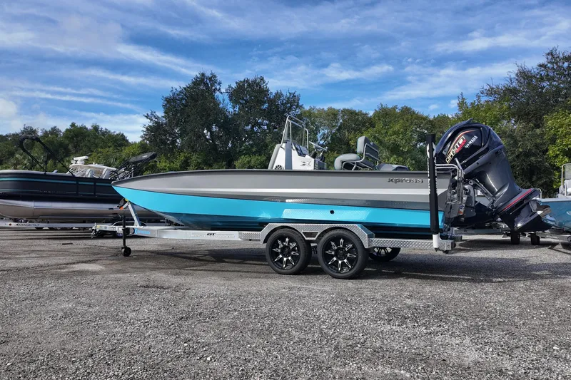 Slide: The Image of 2026 Xpress X23B Bay Lounge boat on trailer, parked outdoors under blue sky. - 3
