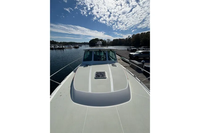 Slide: The Image of 2020 Back Cove 37 yacht docked, showcasing sleek design under a partly cloudy sky. - 13