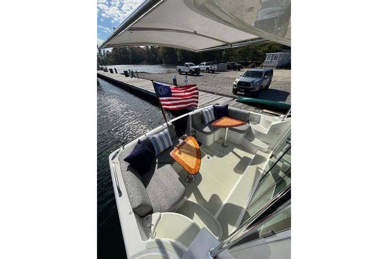 Slide: The Image of 2020 Back Cove 37 boat with American flag, docked by a scenic waterfront. - 17
