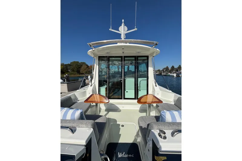 Slide: The Image of 2020 Back Cove 37 boat with outdoor seating and wooden tables, docked under clear blue sky. - 19