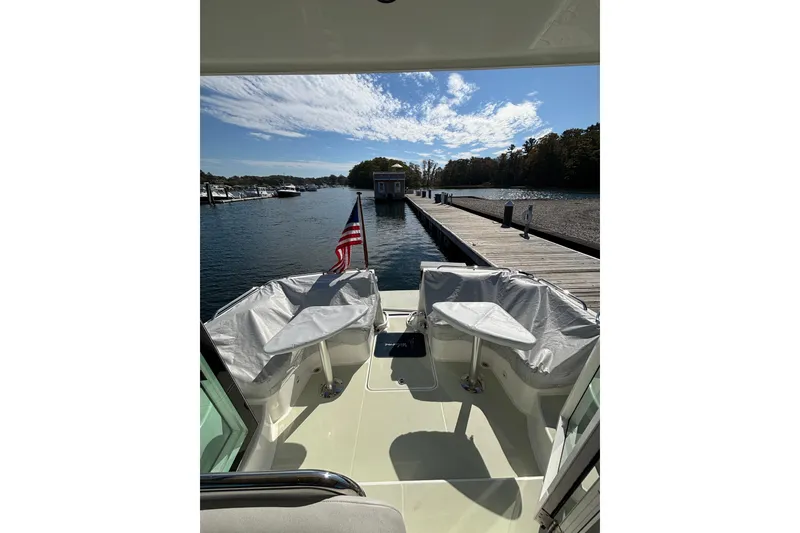 Slide: The Image of 2020 Back Cove 37 boat docked, featuring covered seating and American flag. - 8