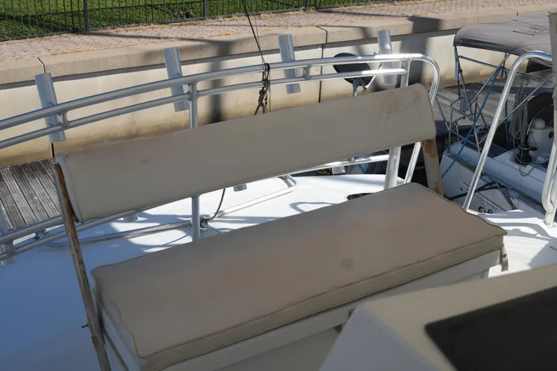 Slide: The Image of 1977 Bertram 46.6 boat with cushioned seating on deck, docked at marina. - 12