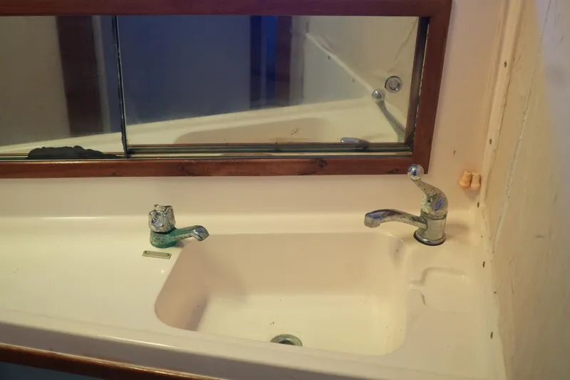 Slide: The Image of 1977 Bertram 46.6 yacht bathroom sink with dual faucets and mirror. - 24