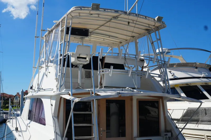 Slide: The Image of 1977 Bertram 46.6 yacht with flybridge, docked under clear blue sky. - 3