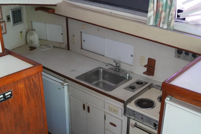 Slide: The Image of 1977 Bertram 46.6 yacht kitchen with sink, stove, and wooden cabinetry. - 33