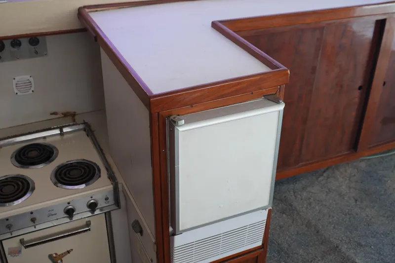 Slide: The Image of 1977 Bertram 46.6 yacht kitchen with stove, fridge, and wooden cabinetry. - 35