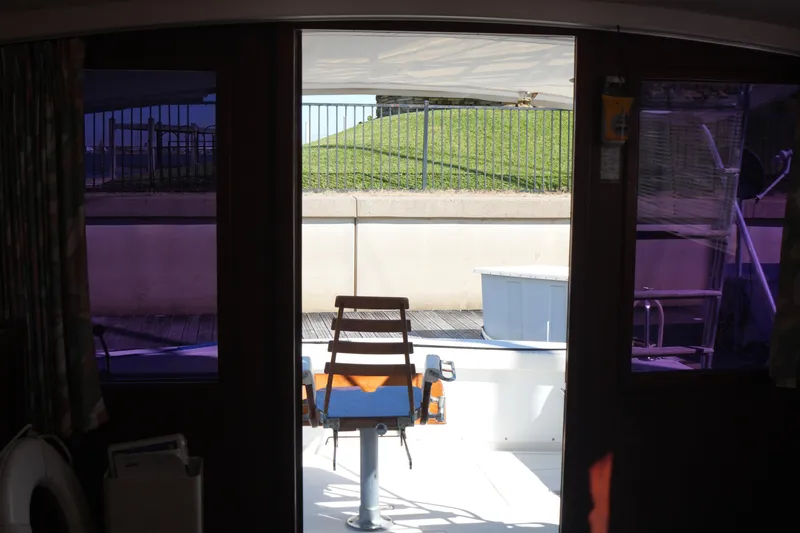 Slide: The Image of Interior view of a 1977 Bertram 46.6 yacht, featuring a chair and outdoor deck. - 38