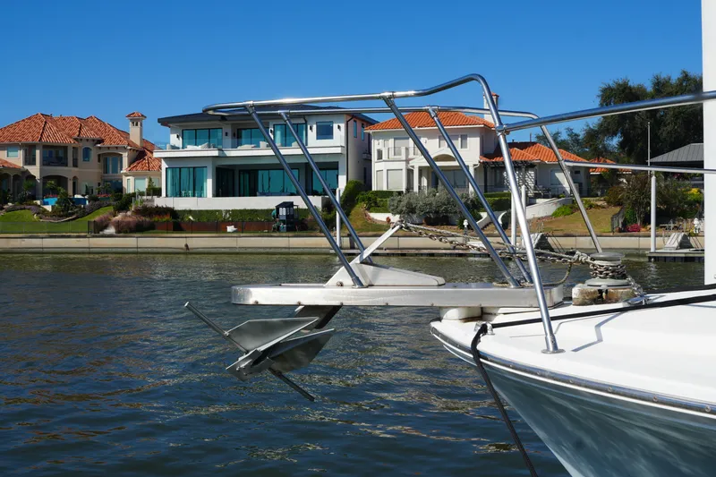 Slide: The Image of 1977 Bertram 46.6 yacht anchored near waterfront homes, clear blue sky. - 4
