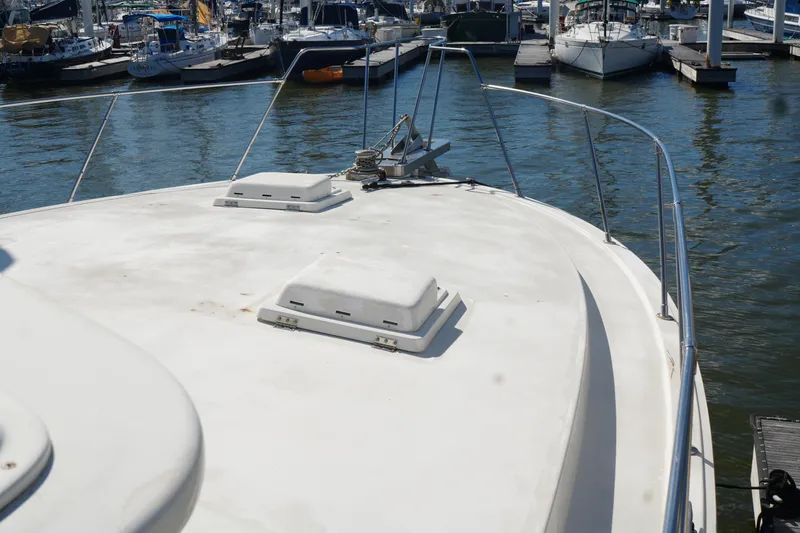 Slide: The Image of 1977 Bertram 46.6 yacht bow view at marina, showcasing deck and railing. - 6