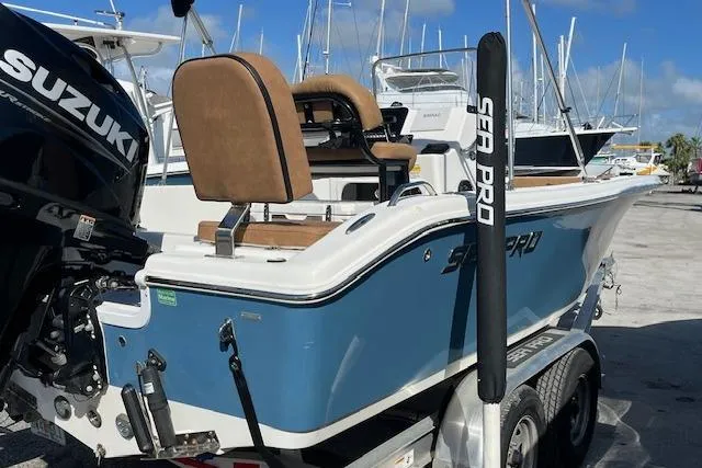 Slide: The Image of 2024 Sea Pro 199 Center Console boat on trailer, featuring Suzuki engine, docked at marina. - 9
