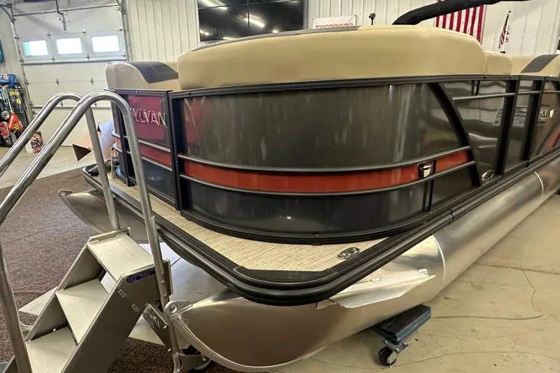 Slide: The Image of 2025 Sylvan L1 DLZ pontoon boat in showroom with metal stairs. - 2