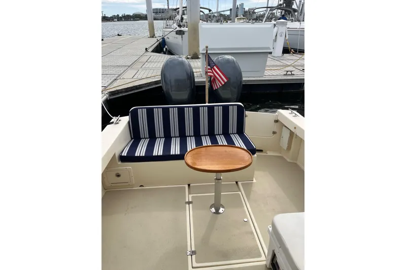 Slide: The Image of 2020 Eastern 27 Islander boat interior with striped seating and wooden table at dock. - 10