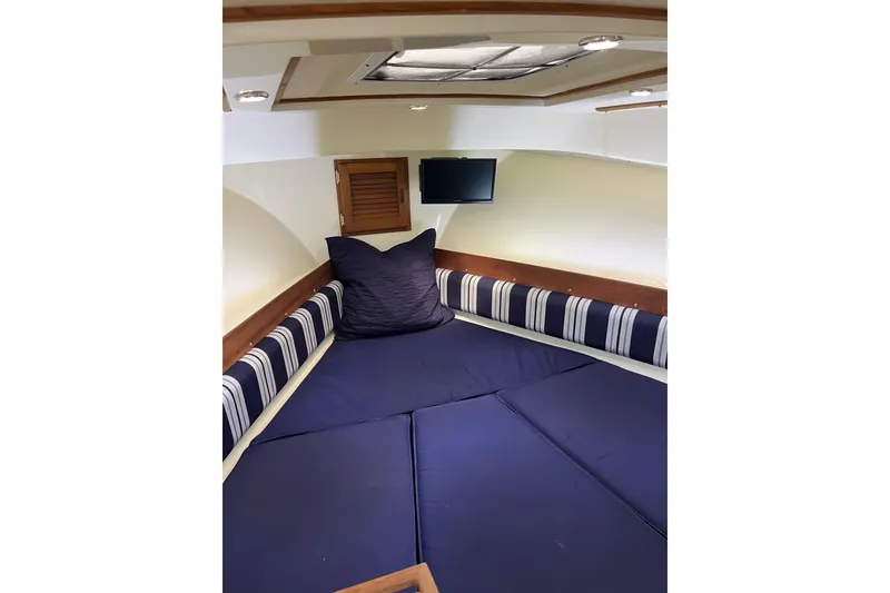 Slide: The Image of 2020 Eastern 27 Islander cabin interior with blue cushions and striped accents. - 13