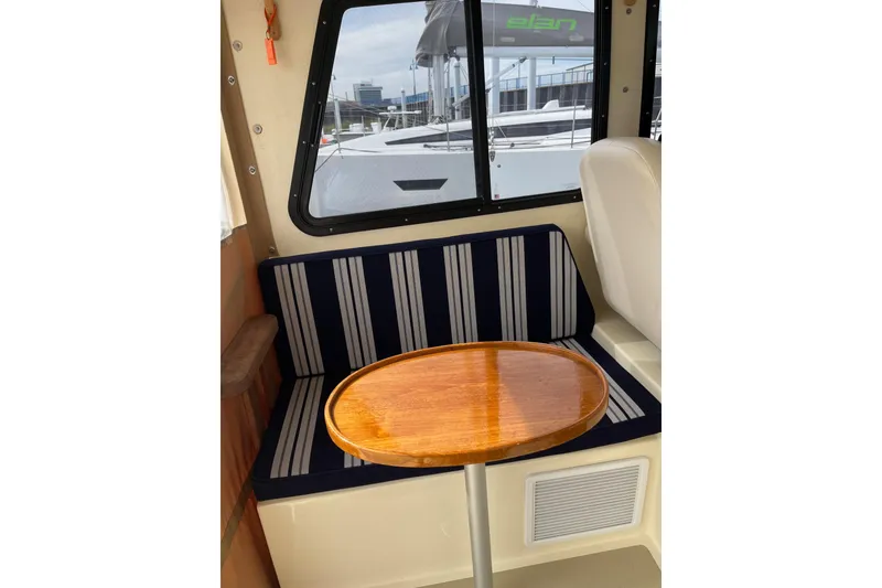 Slide: The Image of Interior of 2020 Eastern 27 Islander boat with striped seating and wooden table. - 8