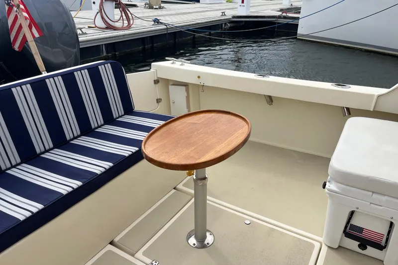 Slide: The Image of Cozy seating area on 2020 Eastern 27 Islander boat with striped cushions and wooden table. - 9