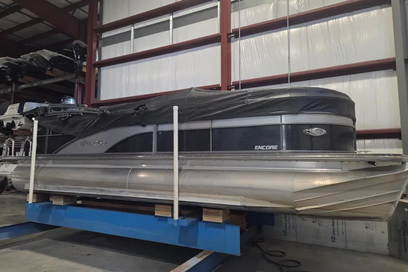The Image of 2019 Manitou 23 Encore SHP pontoon boat in storage, covered and elevated indoors. - 0