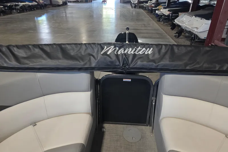 Slide: The Image of 2019 Manitou 23 Encore SHP boat interior with seating and cover in storage facility. - 9