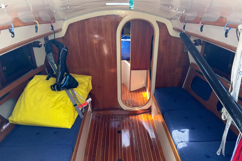 Slide: The Image of 1982 J Boats J/30 cabin interior with wooden finish and blue cushions. - 7