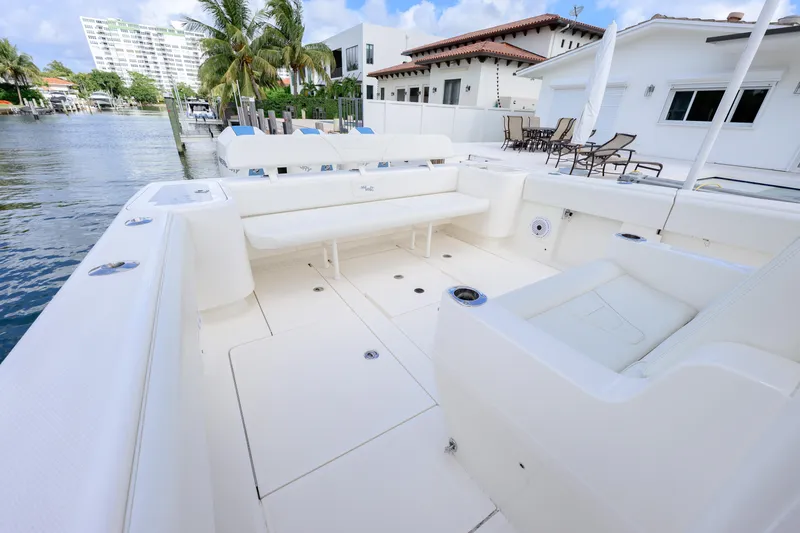 Slide: The Image of 2023 SeaVee 370z boat with spacious white deck and seating, docked by waterfront homes. - 11