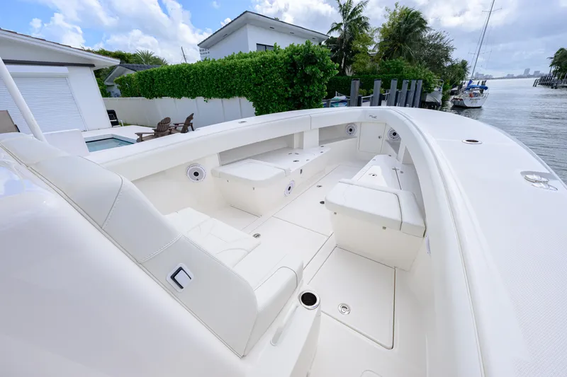 Slide: The Image of 2023 SeaVee 370z boat interior with white seating, docked by a waterfront home. - 12