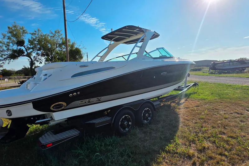 Slide: The Image of 2009 Sea Ray 270 SLX boat on trailer, parked on grass under sunny sky. - 6