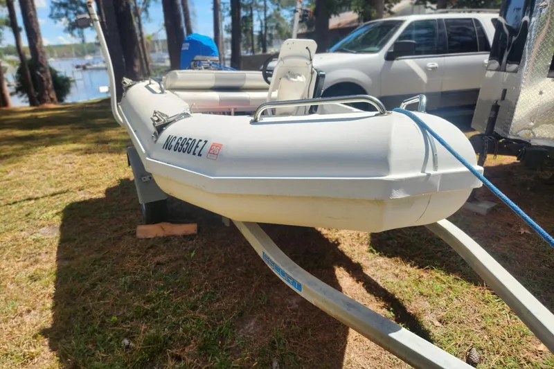 Slide: The Image of 2011 Bullfrog 10' Yacht Tender on trailer, parked near a lake with trees. - 2