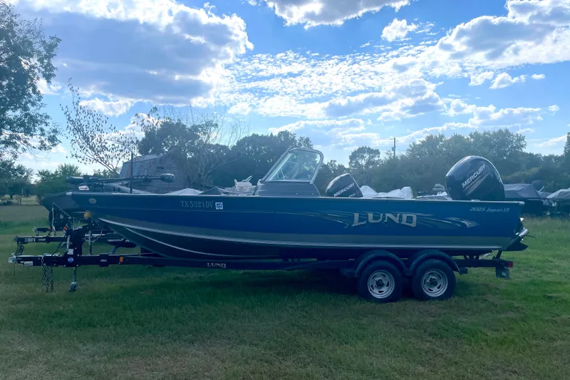 The Image of 2017 Lund 2025 Impact XS boat on trailer under a blue sky. - 1