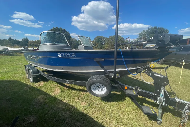 Slide: The Image of 2017 Lund 2025 Impact XS boat on trailer in grassy area under blue sky. - 4