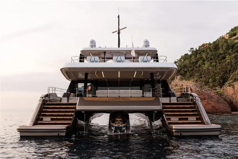 Slide: The Image of 2026 Sunreef 80 Sunreef Power yacht on water, rear view, near rocky coastline. - 10