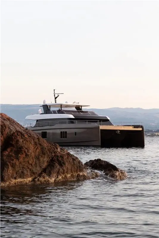 Slide: The Image of 2026 Sunreef 80 Sunreef Power yacht on calm waters near rocky shore. - 15
