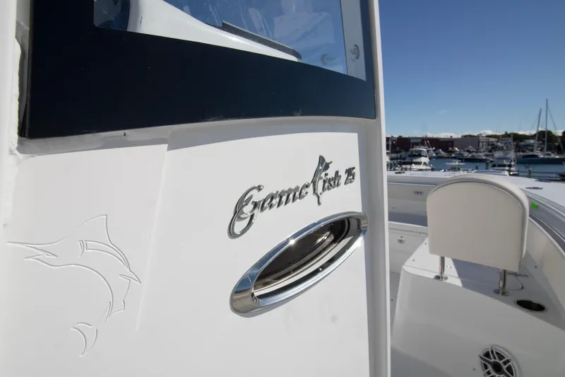 Slide: The Image of 2026 Sea Hunt Gamefish 25 boat detail with logo, docked in marina under clear sky. - 5