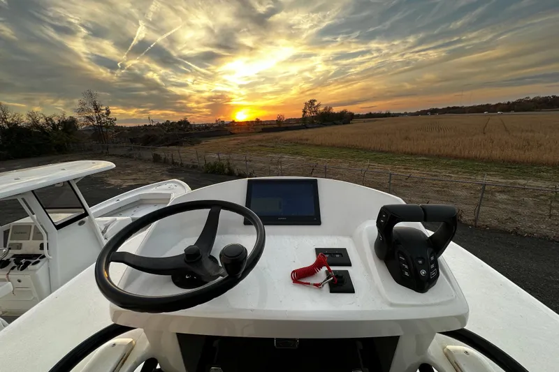 Slide: The Image of 2024 Pair Customs 24DV boat helm with sunset view, featuring steering wheel and controls. - 23