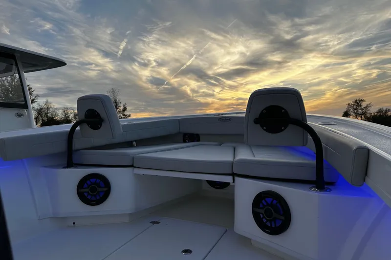 Slide: The Image of 2024 Pair Customs 24DV boat interior with sunset sky, featuring cushioned seating and blue LED lights. - 21