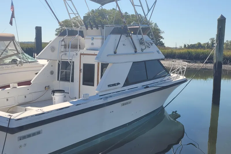 The Image of 1990 Phoenix 29 SFX Convertible boat docked in calm waters. - 0