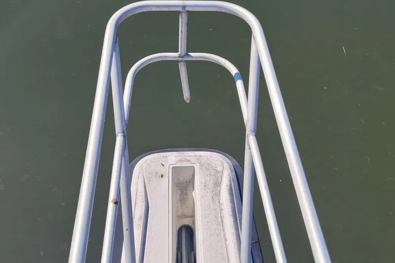 Slide: The Image of Bow view of 1990 Phoenix 29 SFX Convertible boat with metal railings over water. - 12