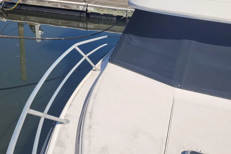 Slide: The Image of 1990 Phoenix 29 SFX Convertible boat deck with railing, docked at marina. - 13