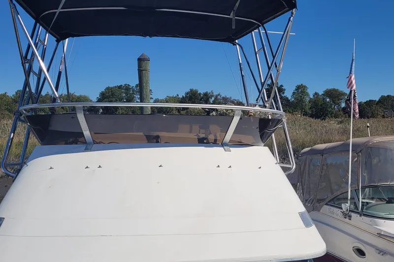 Slide: The Image of 1990 Phoenix 29 SFX Convertible boat with canopy, docked beside another vessel. - 16