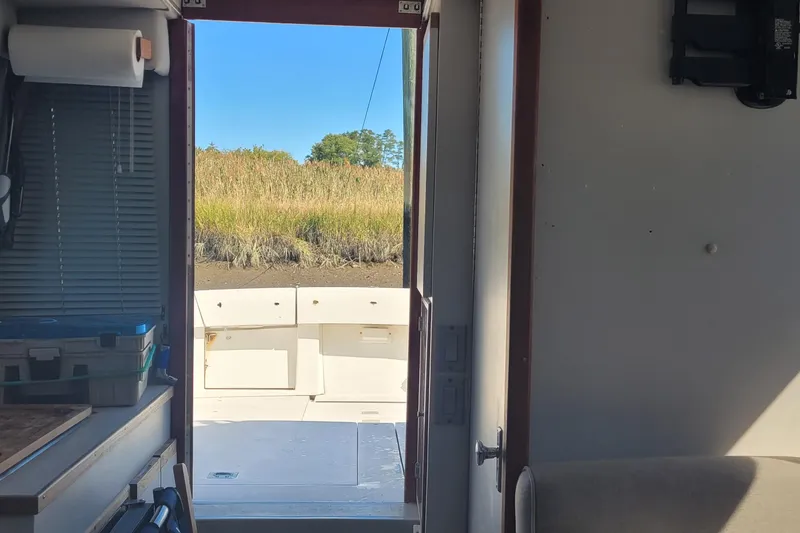 Slide: The Image of Interior view of 1990 Phoenix 29 SFX Convertible boat, showing open door to deck and grassy landscape. - 28