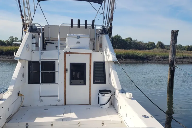 Slide: The Image of 1990 Phoenix 29 SFX Convertible boat docked by a serene riverbank. - 3