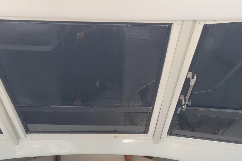 Slide: The Image of 1990 Phoenix 29 SFX Convertible boat window with metal latches and dark tinted glass. - 33