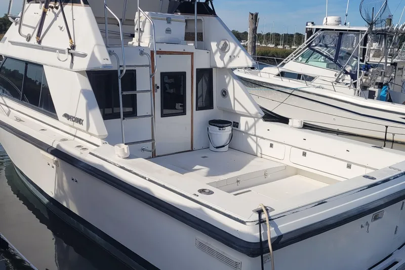 Slide: The Image of 1990 Phoenix 29 SFX Convertible boat docked, featuring spacious deck and sleek design. - 4