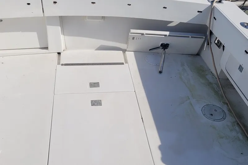 Slide: The Image of 1990 Phoenix 29 SFX Convertible boat deck with storage compartments and fishing rod holder. - 7