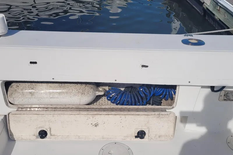 Slide: The Image of 1990 Phoenix 29 SFX Convertible boat deck with storage compartment and coiled blue hose. - 8