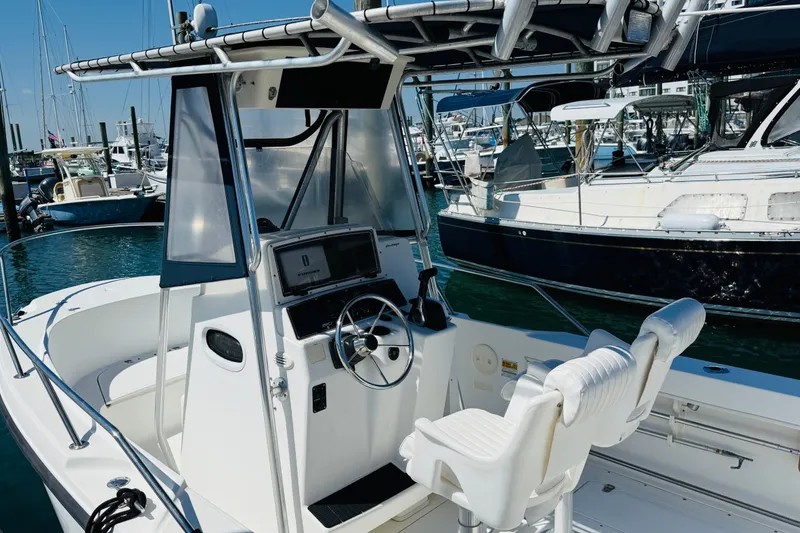 Slide: The Image of 2000 Boston Whaler 21 Outrage boat interior at marina, featuring helm and seating. - 6