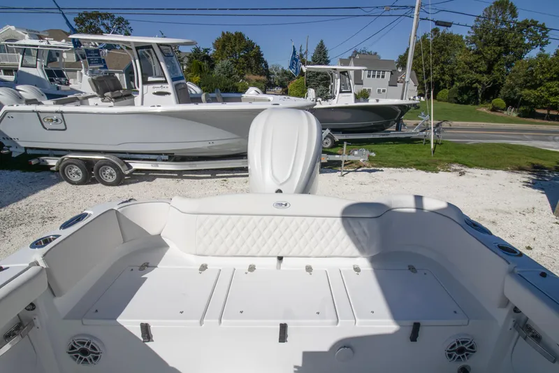 Slide: The Image of 2026 Sea Hunt Ultra 255 SE boat interior with seating and storage, parked outdoors. - 10