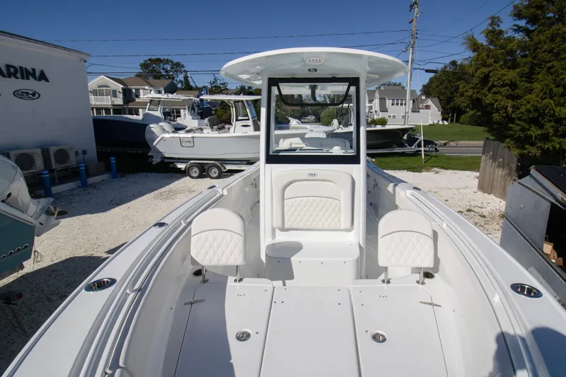 Slide: The Image of 2026 Sea Hunt Ultra 255 SE boat docked at a marina under clear blue skies. - 2